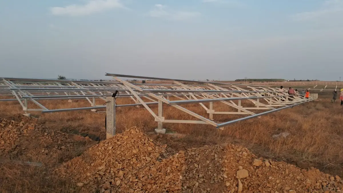Rows of galvanised module mounting structures going up across the Mahagenco Bilur site at golden hour