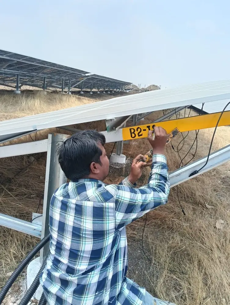 Technician labelling a module mounting structure beneath installed solar modules