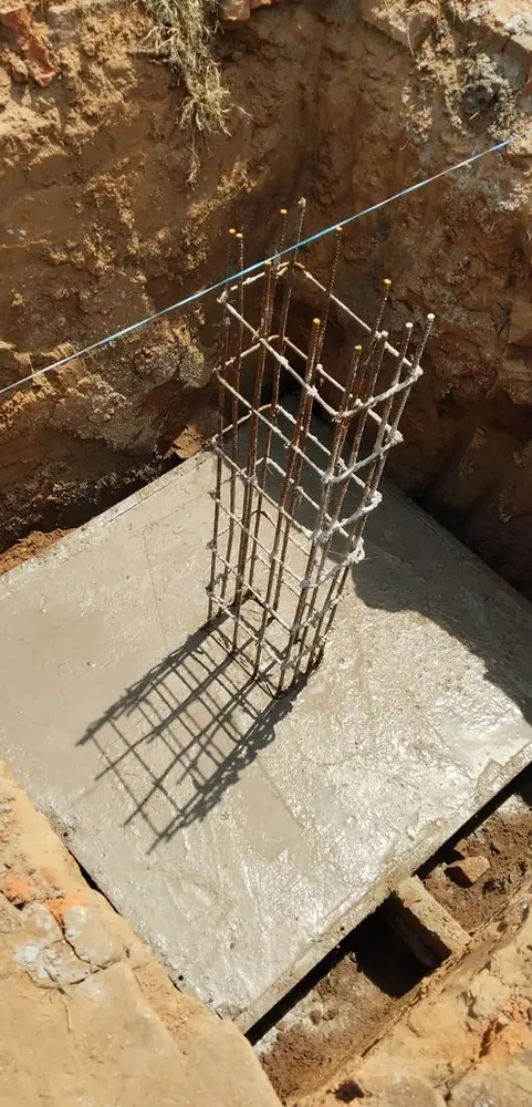 Freshly poured concrete footing around a column reinforcement cage
